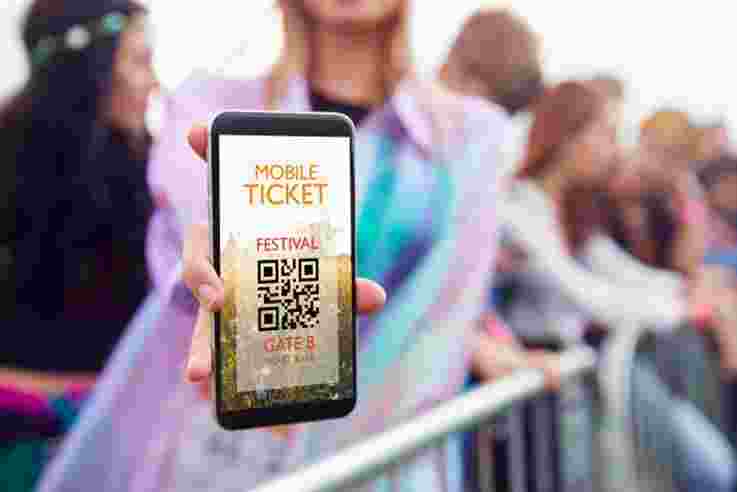 Close Up Of Woman Holding Mobile Ticket On Screen To Camera As She Arrives At Entrance To Music Festival