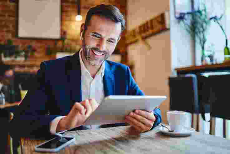 Businessman working on digital tablet while having coffee in cafe