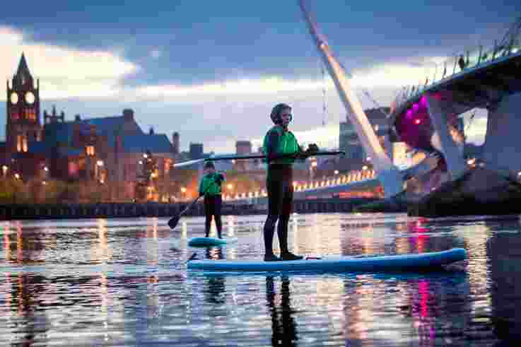 Friends stand-up paddle boarding on the River Foyle