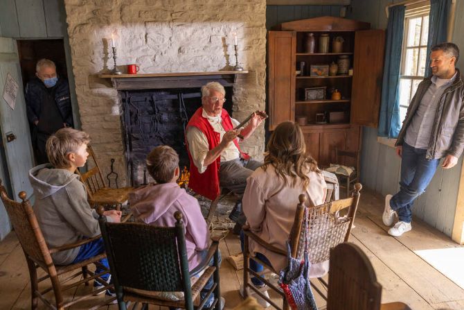 A man sharing a story at the Ulster American Folk Park, with a family gathered around listening