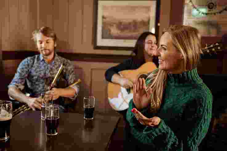 Tourist enjoying music and drinks as part of Belfast Traditional Music Trail
