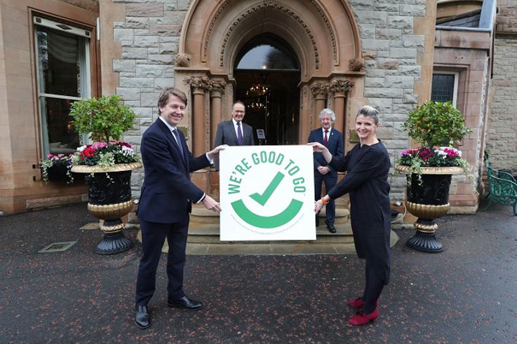 4 individuals pictured outside the Culloden holding a "We're Good to Go" sign