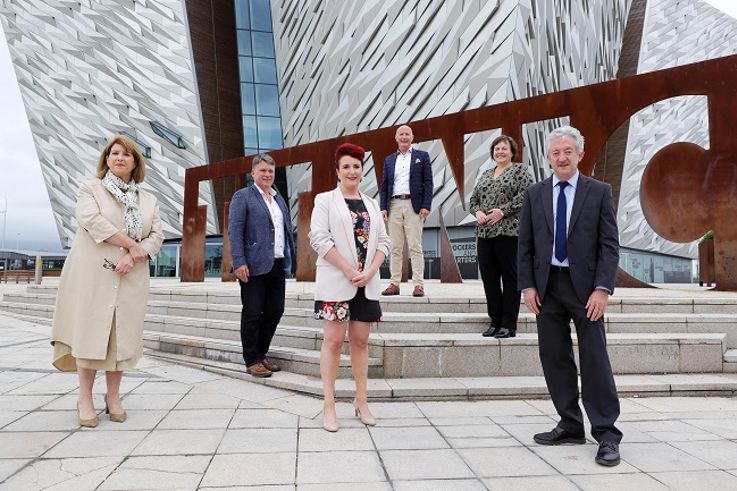 Group of individuals pictured outside Titanic Belfast, smiling at the camera.
