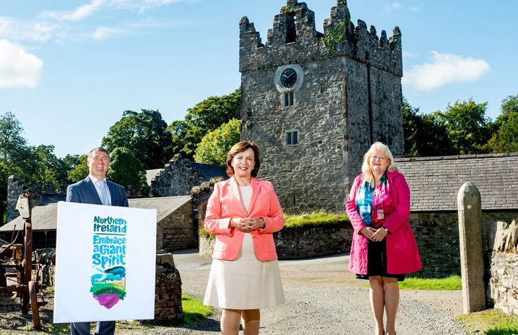 3 individuals pictured outside historic building, smiling at the camera