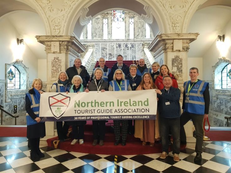 Members pictured at Belfast City Hall holding a Northern Ireland Tourist Guide Association (NITGA) banner.