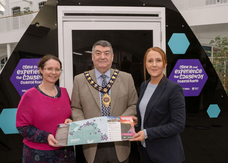 A man and two women pictured holding a map, in celebration of the Igloo Dome in Carrick.
