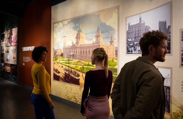 A group of people observing an exhibition, engaging in conversation and looking at the display.